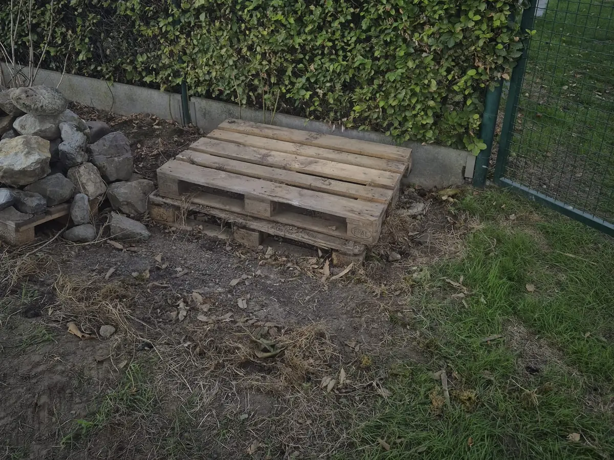 Lege pallet en opgeruimde tuinhoek nadat JG Services de natuursteen heeft afgevoerd
