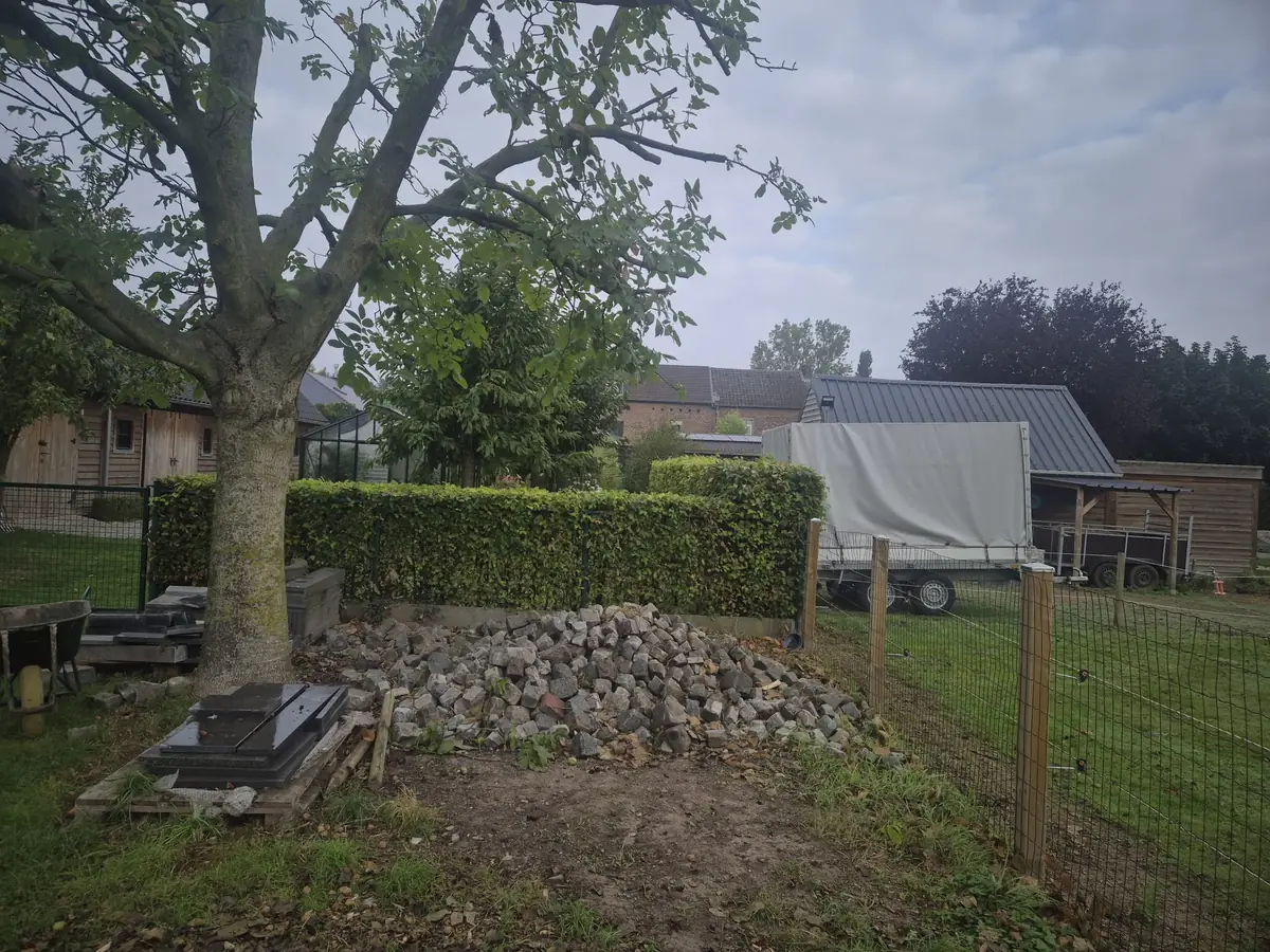 Hoop kasseien en puin naast een haag voor de opruiming door JG Services in Limburg