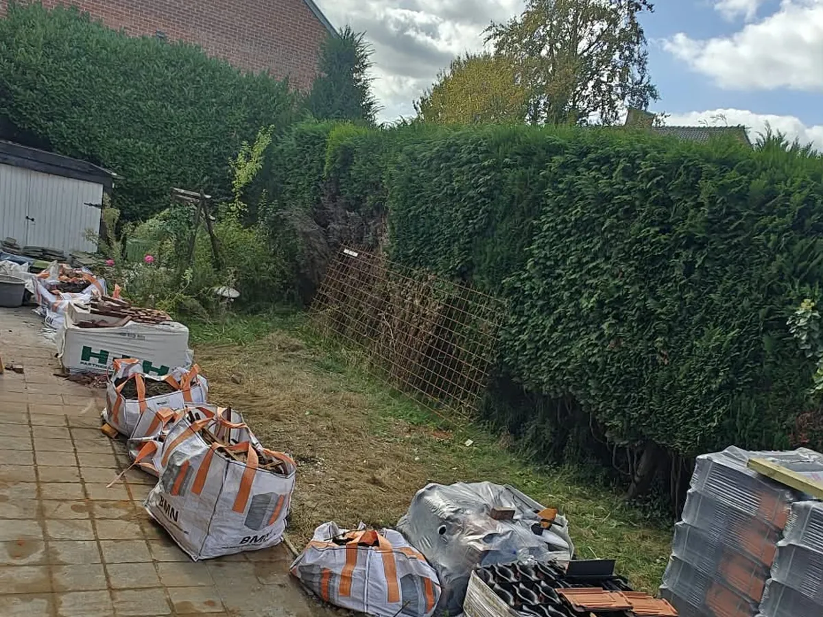 Hetzelfde tuinpad vrijgemaakt na het afvoeren van het sloopafval, enkel de big bags van de dakwerker blijven staan